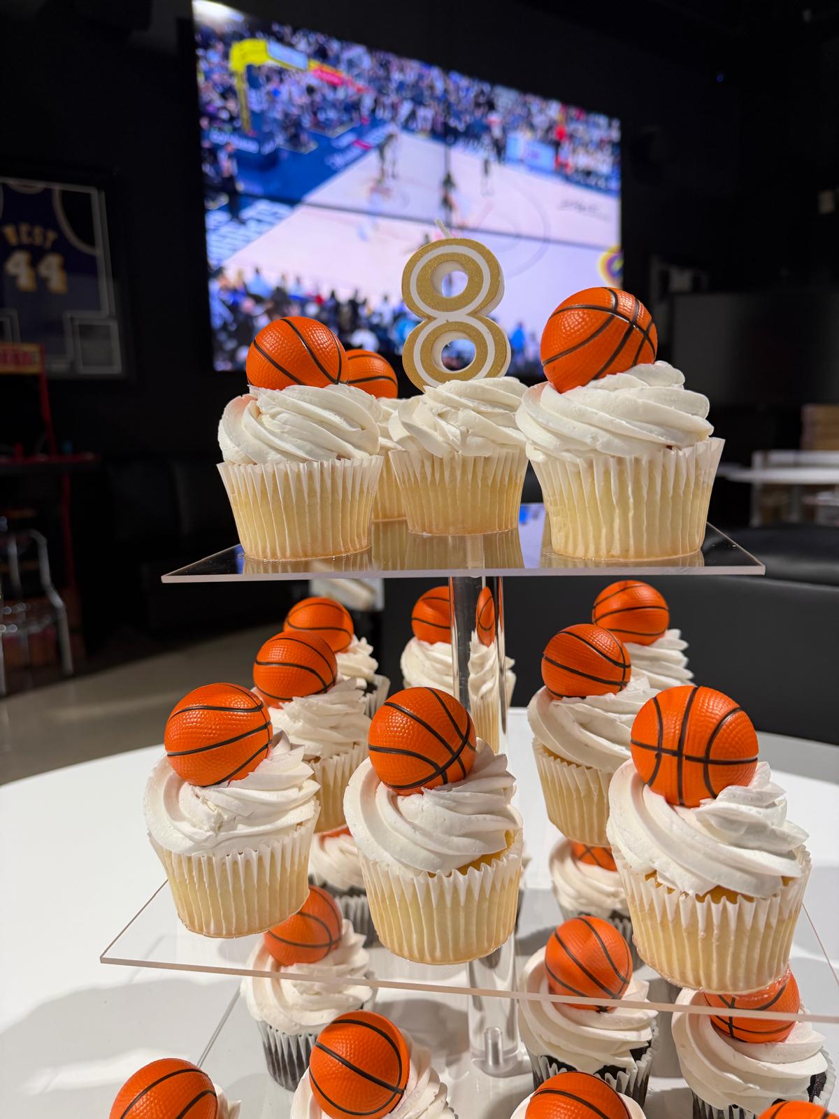 A tiered basketball-themed cupcake display with an 8 candle for a Swysh Den birthday party