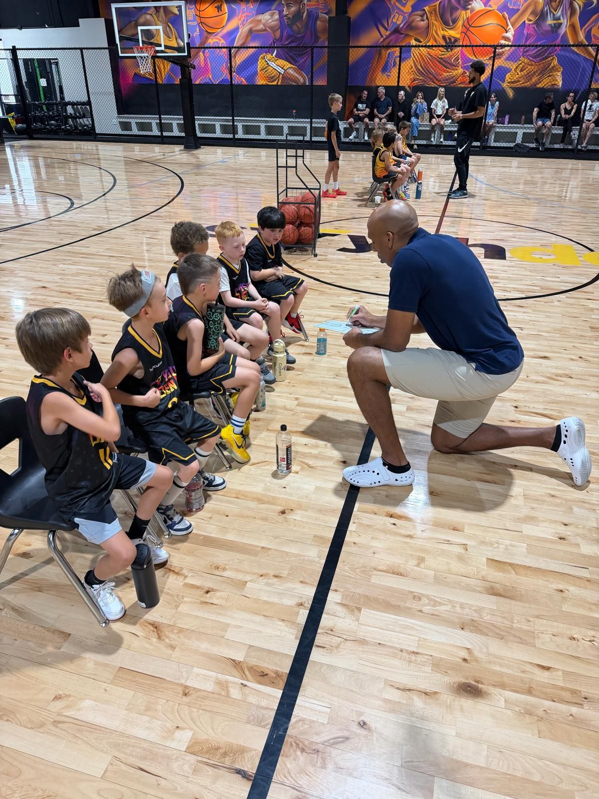 A coach draws up a play for his Swysh Den team courtside