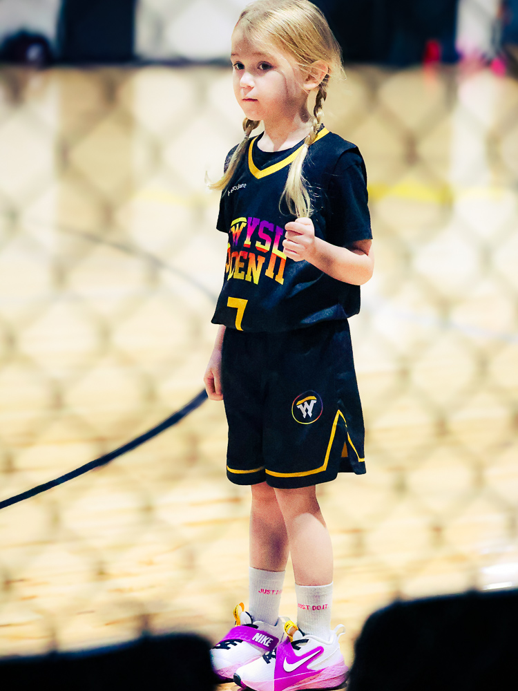 A young girl in a Swysh Den II jersey stands ready on the court
