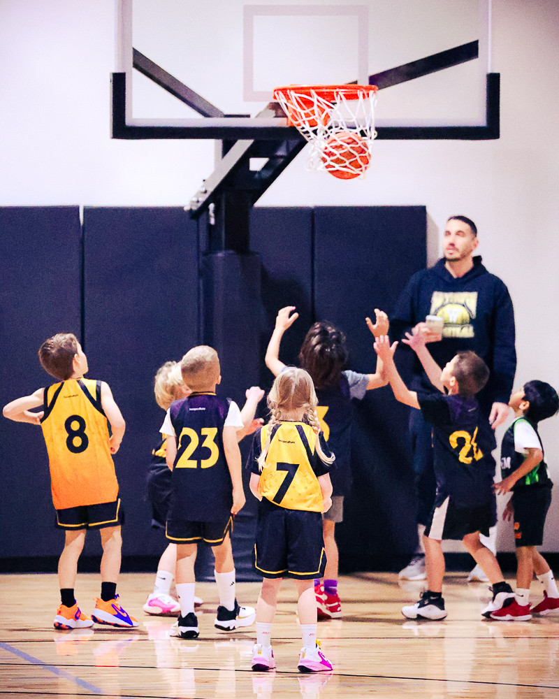 A group of young kids high-five their coach after a basket at Swysh Den